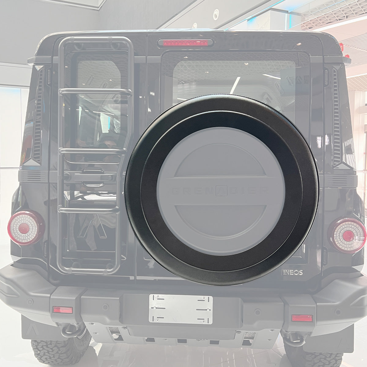 PLOMOR Donut Spare Tire Cover securely installed on the INEOS Grenadier rear, featuring the open center design that enhances the rugged off-road aesthetic while ensuring a snug fit.