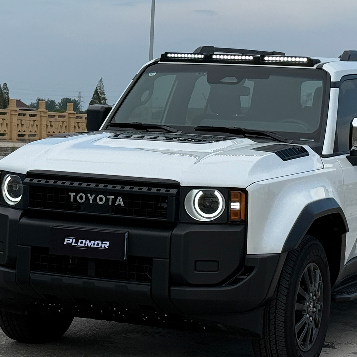 Low-profile ABS roof light cover for Toyota LC250, featuring triple LED array, glossy black finish, and drill-free 3M tape installation.