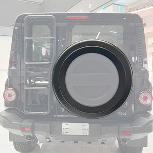 PLOMOR Donut Spare Tire Cover securely installed on the INEOS Grenadier rear, featuring the open center design that enhances the rugged off-road aesthetic while ensuring a snug fit.