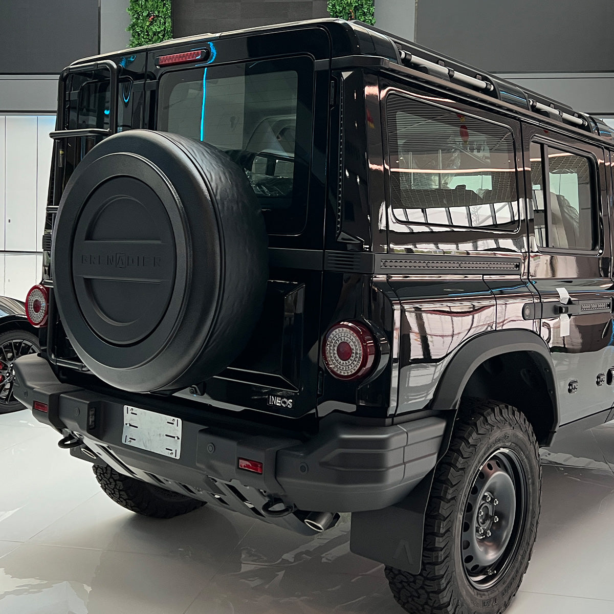 Close-up showing the tough ABS outer shell and flexible leather ring of the PLOMOR Donut Cover, detailing its UV-resistant and scratch-resistant protection for the Grenadier spare whee