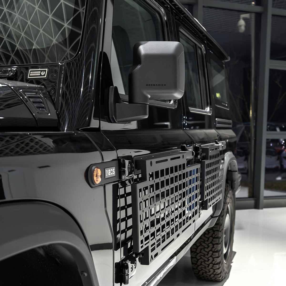 PLOMOR heavy-duty steel body side utility panel for Ineos Grenadier. Features a MOLLE grid system for mounting exterior overlanding and recovery gear.