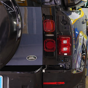 Close-up of PLOMOR LED smoked tail lights on installed Defender L663