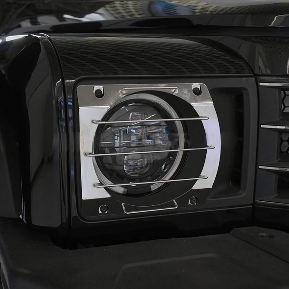 Close-up of black aluminium alloy headlight guard installed on INEOS Grenadier, corrosion-resistant and precision fitted.