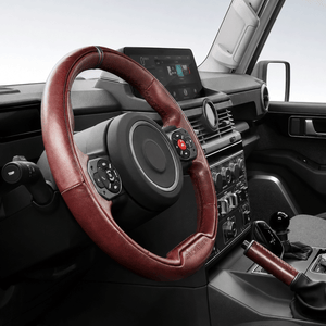Close-up of driving hands holding PLOMOR leather steering wheel cover installed on INEOS Grenadier