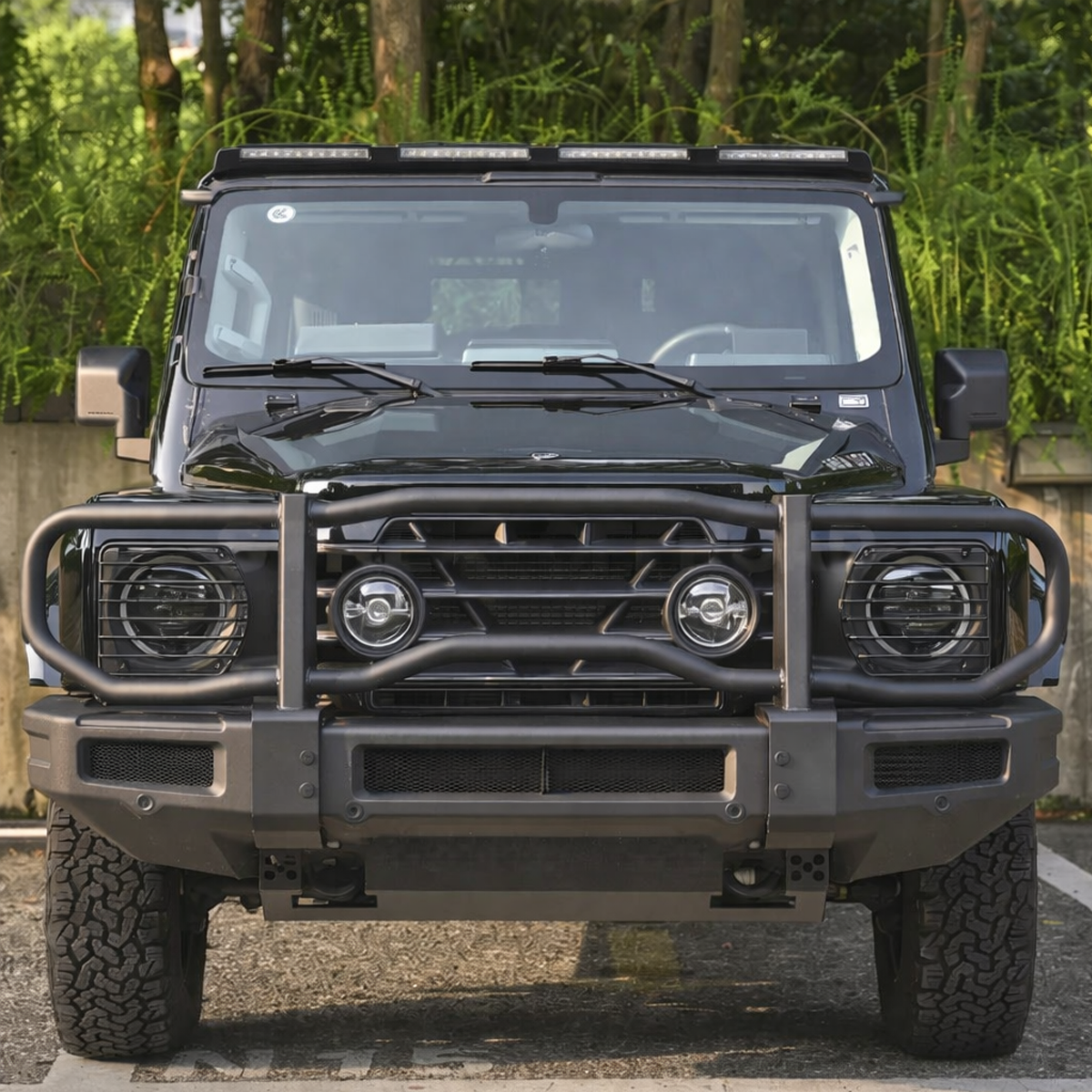 Angled shot of INEOS Grenadier with installed headlight guards, demonstrating precision fit and durable black finish