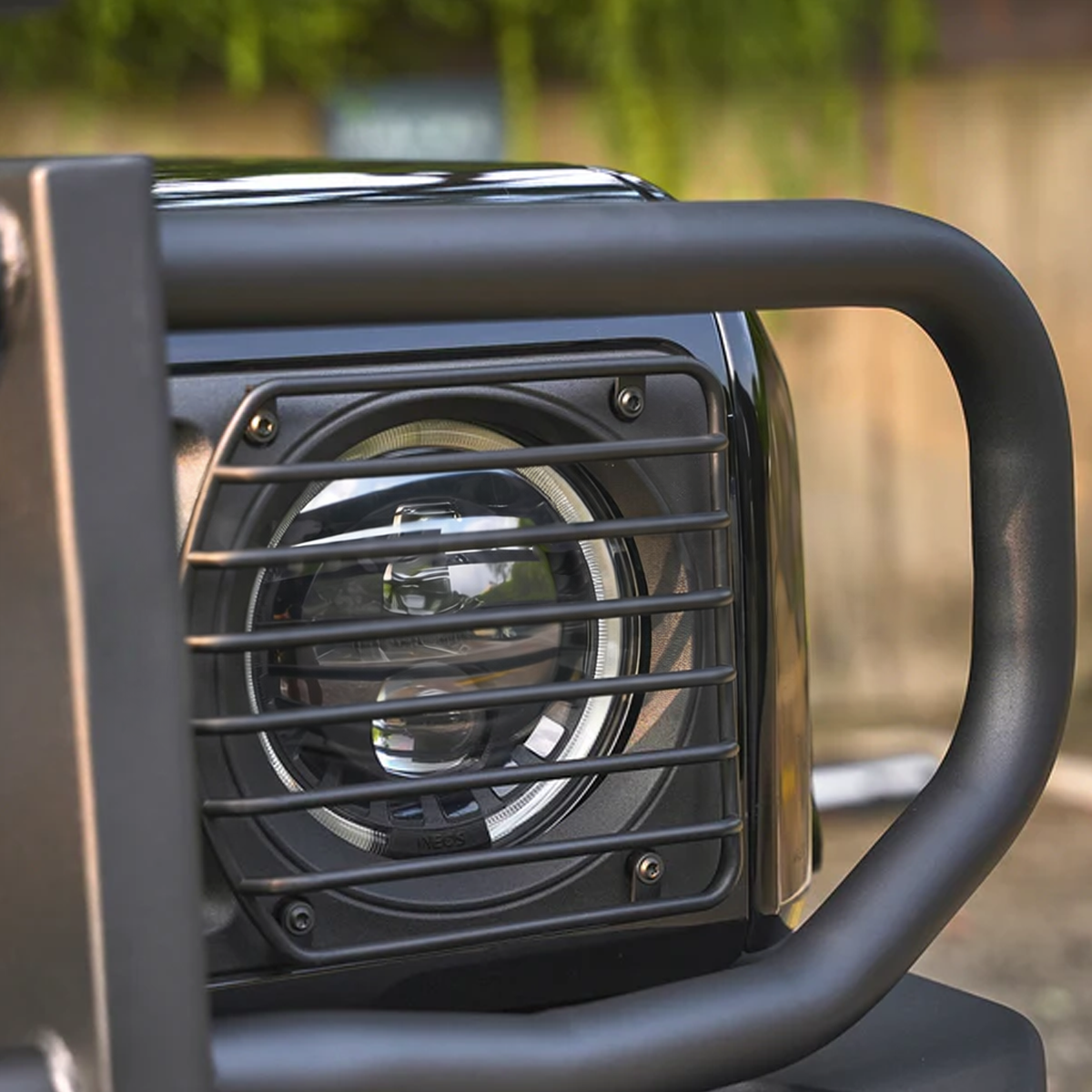 INEOS Grenadier with metal headlight guards installed, showing seamless OEM-style integration and rugged off-road look