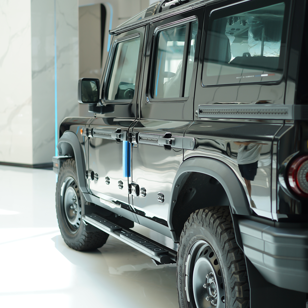 An image showing the Dual-Tube Fixed Side Steps installed on the side of an INEOS Grenadier. The steps are made from black powder-coated aluminium alloy and clearly show the double-bar structure and integrated anti-slip step pads.