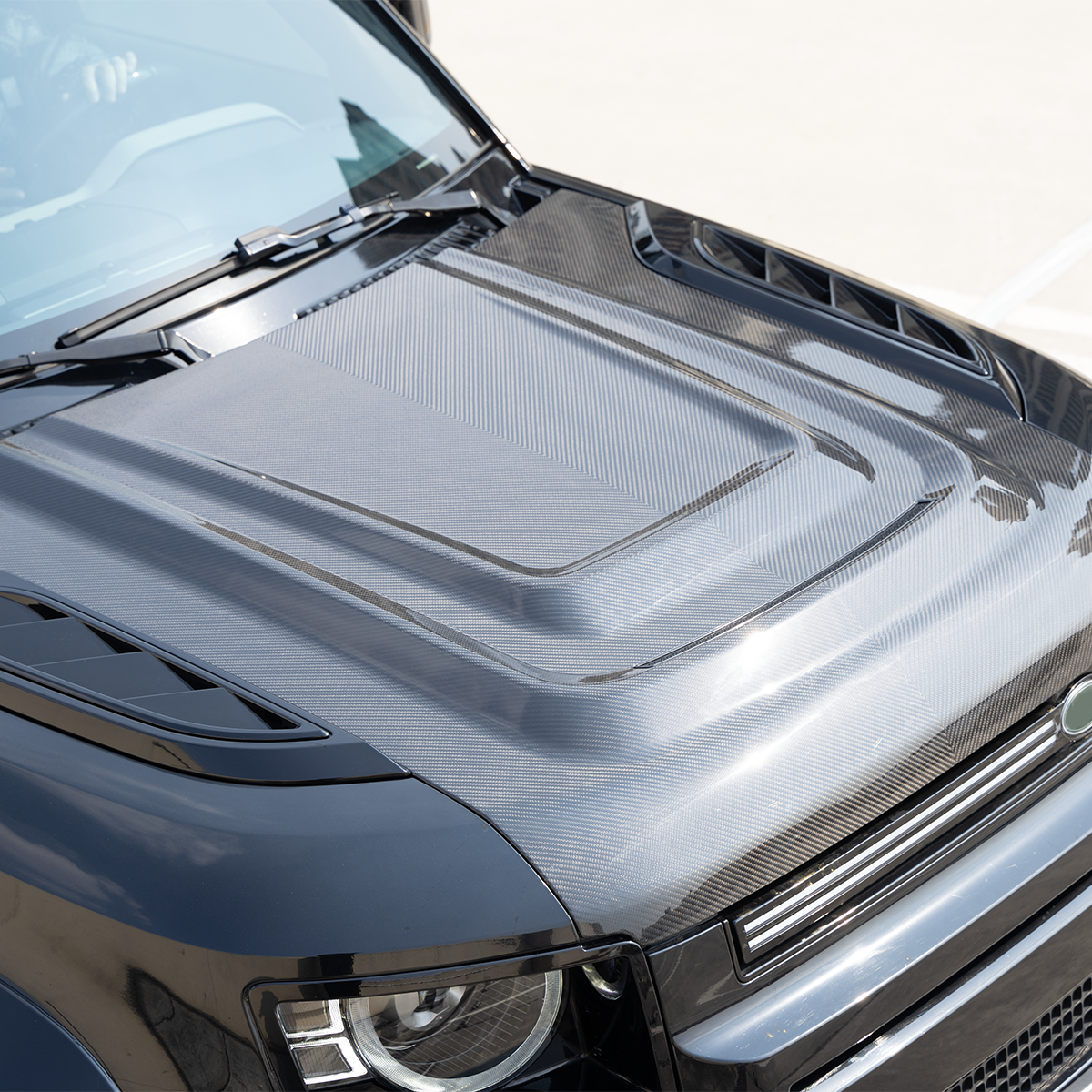 Side view of installed PLOMOR Dry Carbon Bonnet on Defender