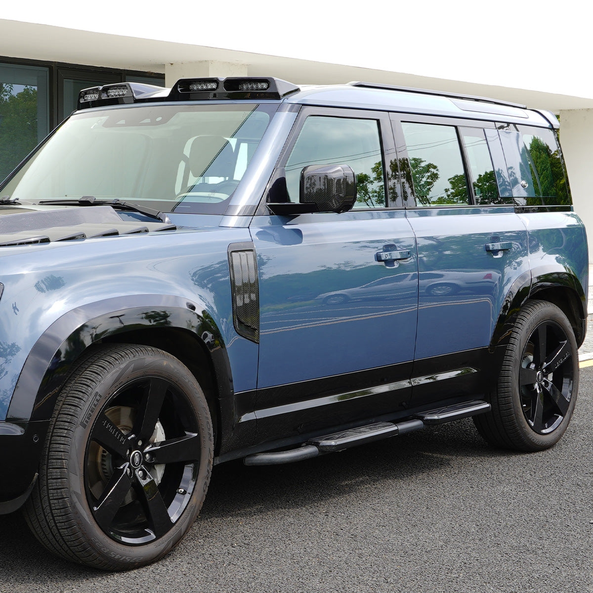 Side view of installed PLOMOR Gloss Black Side Moulding on Defender