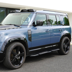 Side view of installed PLOMOR Gloss Black Side Moulding on Defender