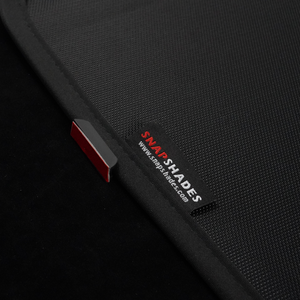 Close-up of skylight sunshade edge showing magnetic clip with 3M tape and woven label on mesh fabric.