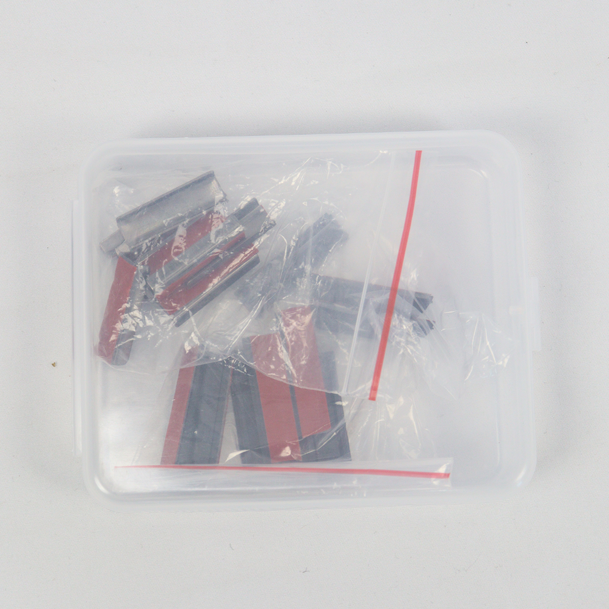 PLOMOR INEOS Grenadier skylight sunshade installation kit — low-profile mounting clips with pre-applied 3M automotive tape, packed in zip bags inside a clear plastic storage box, top-down view