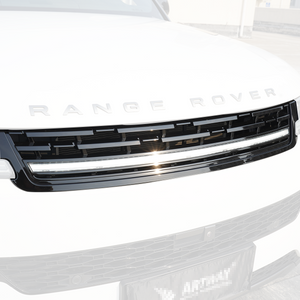 Close-up of a Range Rover front grille with an integrated LED light bar in gloss black finish, daytime shot.