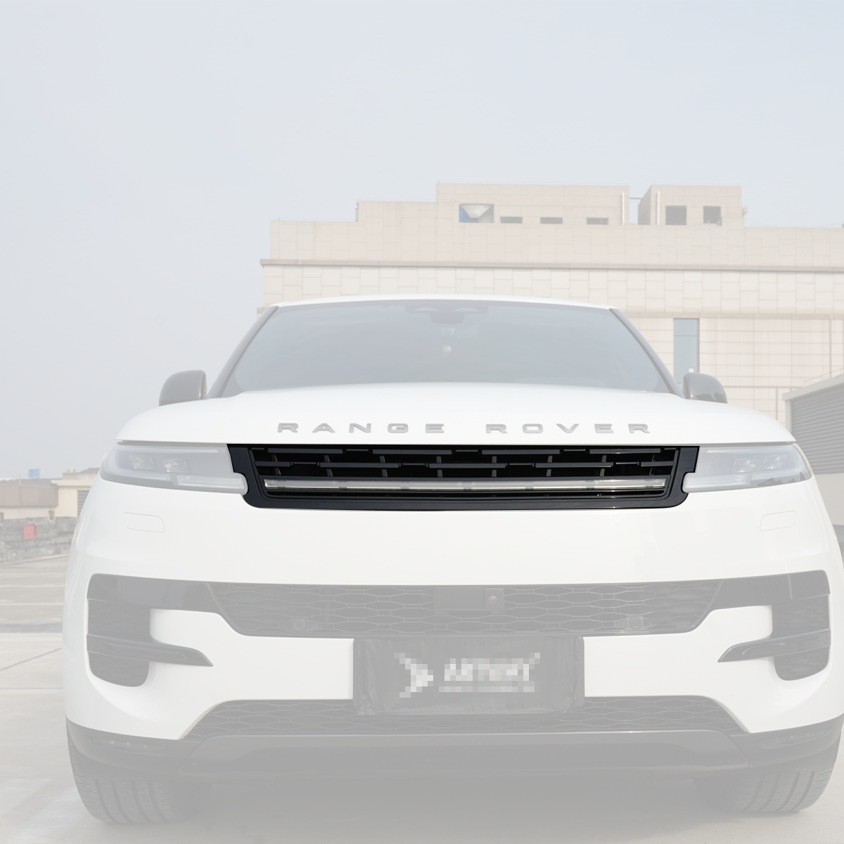 Full front view of a Range Rover featuring a gloss-black front grille with an integrated LED light bar, outdoor daytime scene.