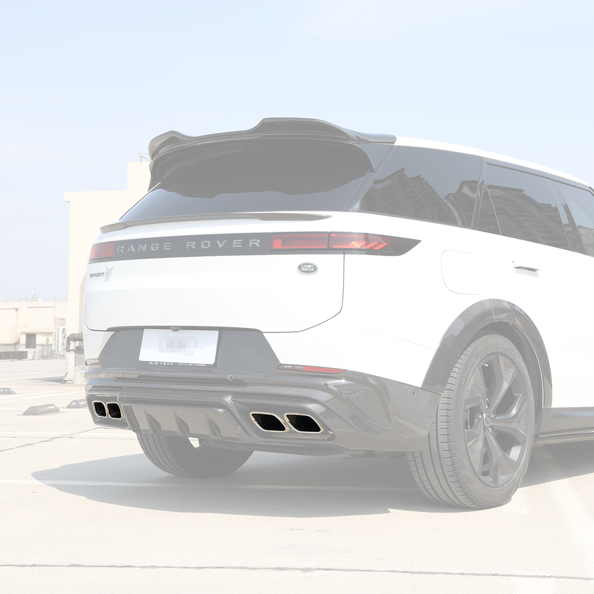 Rear three-quarter view showing quad chrome exhaust tailpipe tips installed with a carbon-fiber rear diffuser on a Range Rover.