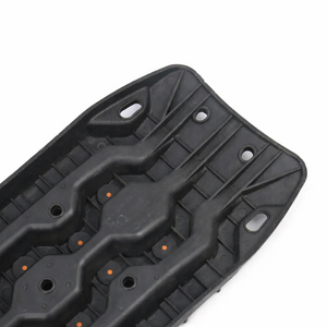 Black off-road recovery traction board with orange cleats, shown in angled three-quarter view on a white background.