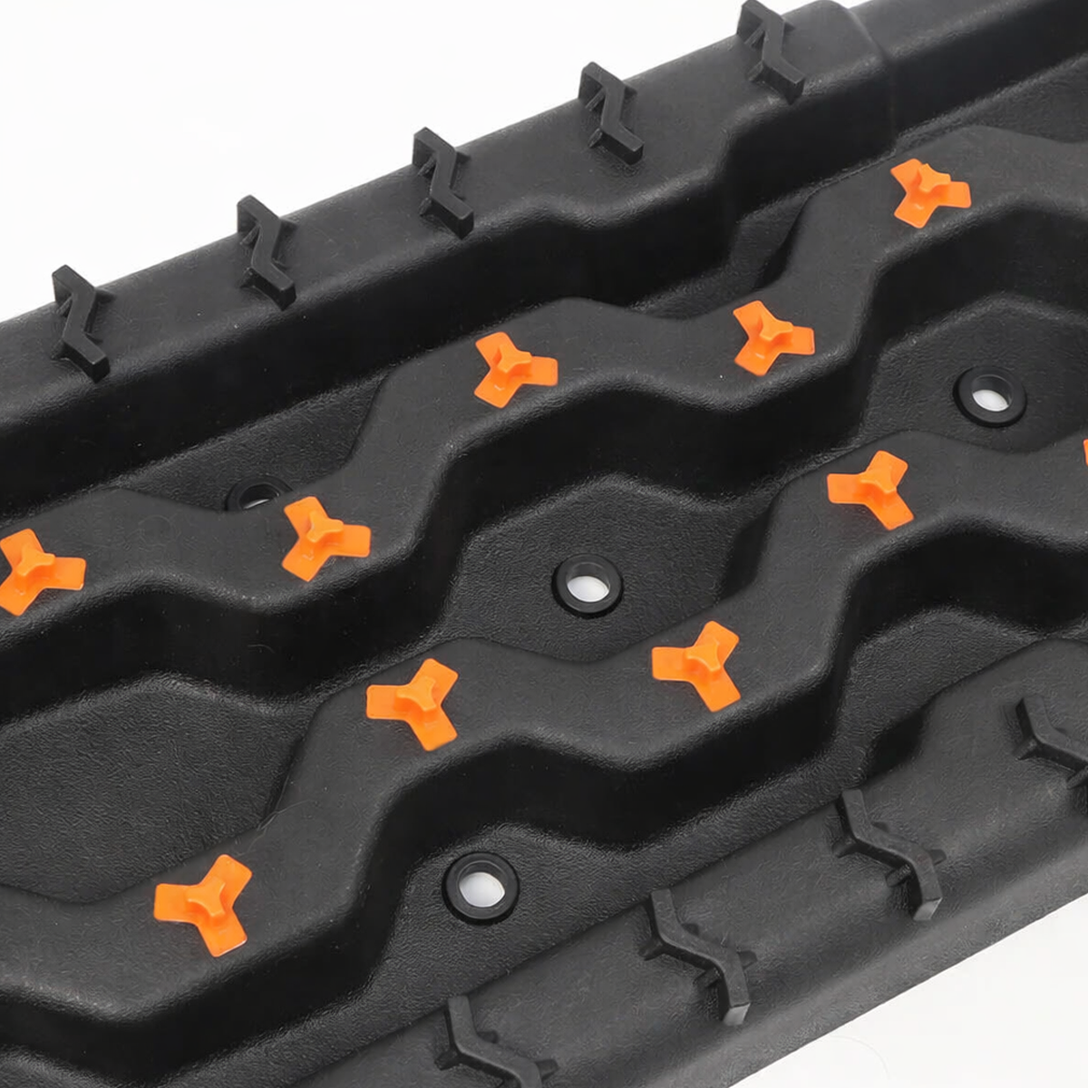 Black off-road recovery traction board with orange cleats, shown in angled three-quarter view on a white background.