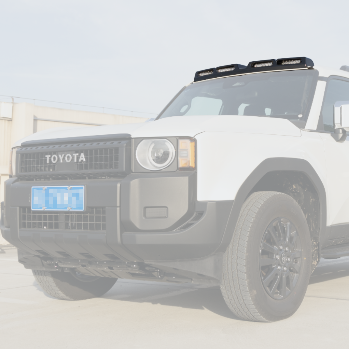 PLOMOR gloss black ABS four-lamp roof lighting cover on Toyota LC250, centered front-on installed view